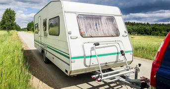 Caravan being towed by a car on a rural road, day.